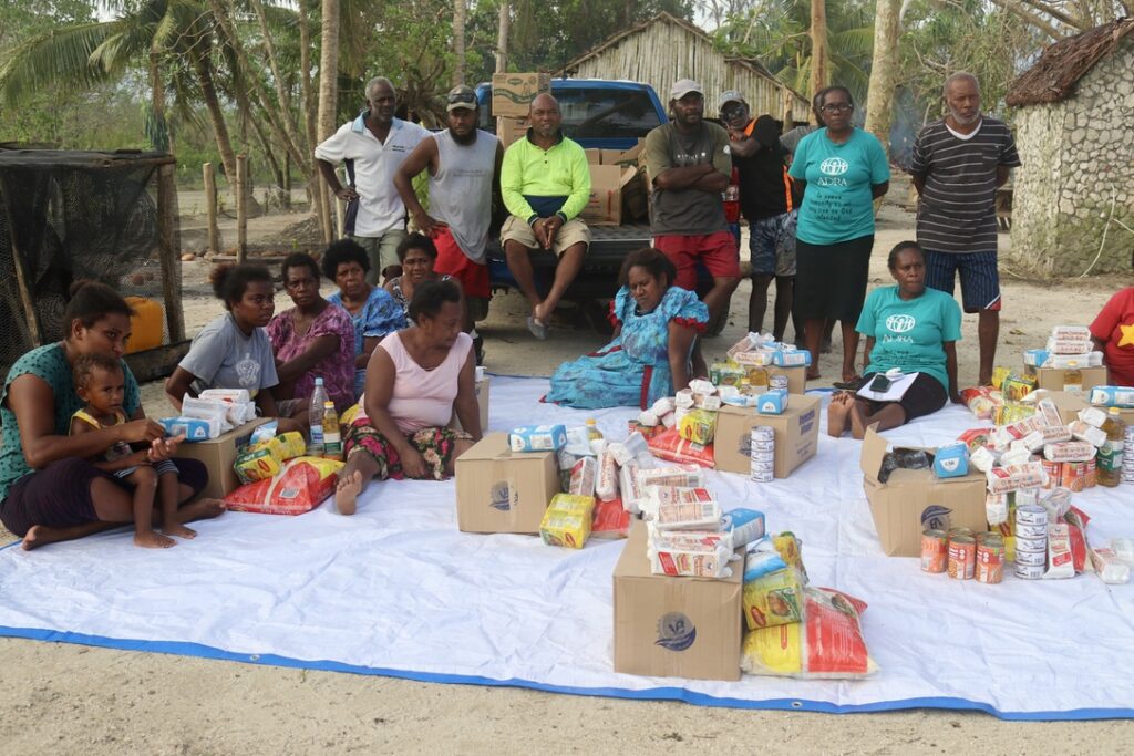 Community members are gathered around emergency food supplies in Efate, Vanuatu