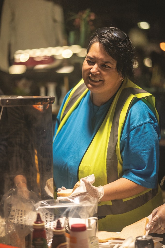 Lady helping to serve a sausage sizzle