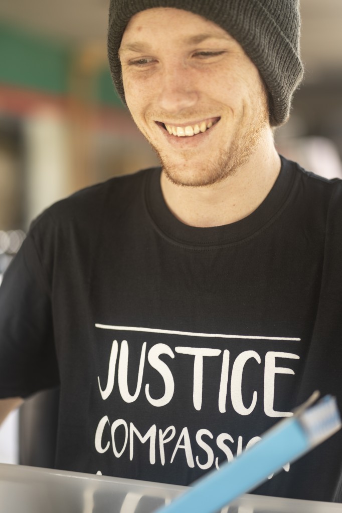 A smiling young man with beanie carrying a box